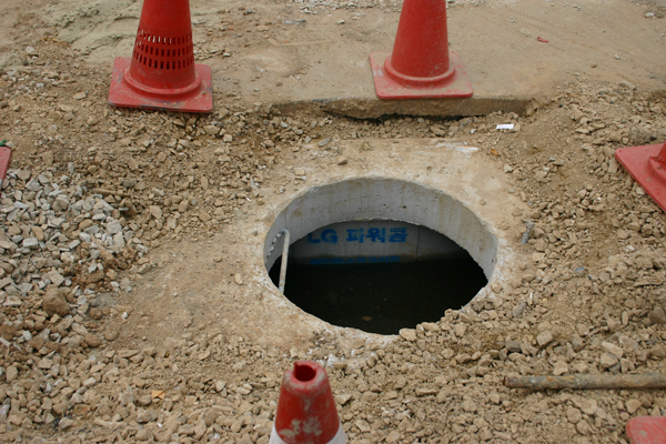 장항중앙초등학교 정문 앞 위 사진의 학교 정문 앞 공사현장의 맨홀이다. 뚜껑이 열려 있고 작업자는 보이지 않은 채 세모꼴 안전 표지판만이 몇 개 놓여 있다. 