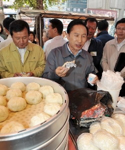 이명박 대통령이 남대문 시장을 방문하는 자리에서 만두를 먹고 있다.