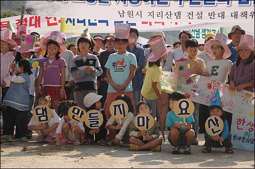 산내어린이집 어린이들이 뙤약볕이 내리쬐는 운동장에 앉아 '댐 만들지 마요'라는 종이피켓을 들고 있다.