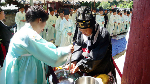  사회자가 읽어 주는 홀기에 따라 알자의 안내를 받은 헌관이 대성전 동쪽에 마련된 대야 물에서 손을 씻고 있습니다.