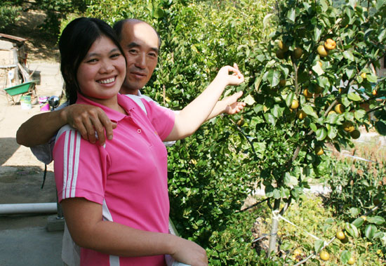 남편 백남수씨와 판티디엔씨가 다정스런 모습으로 정원에 탐스럽게 열린 감을 가리키며 활짝 웃고 있다.