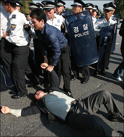 도로 점거 시위 도중 한 시위자가 경찰에 팔이 잡힌 채 도로에 쓰러져 있다.