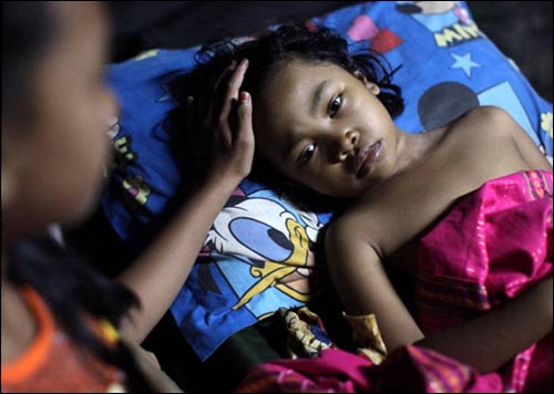 인도네시아를 강타한 지진으로 두 다리가 부러진 소녀가 병원에서 언니의 위로를 받고 있다. 