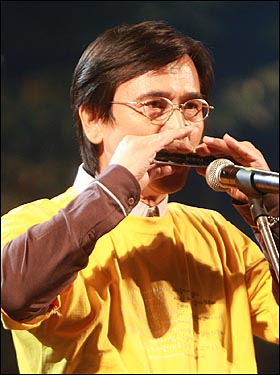 유시민 전 보건복지부 장관이 하모니카로 '행복의 나라'를 연주하고 있다.