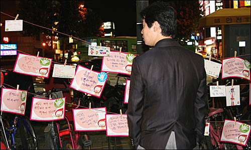 학생들의 그림과 손피켓을 보고 있는 시민.
