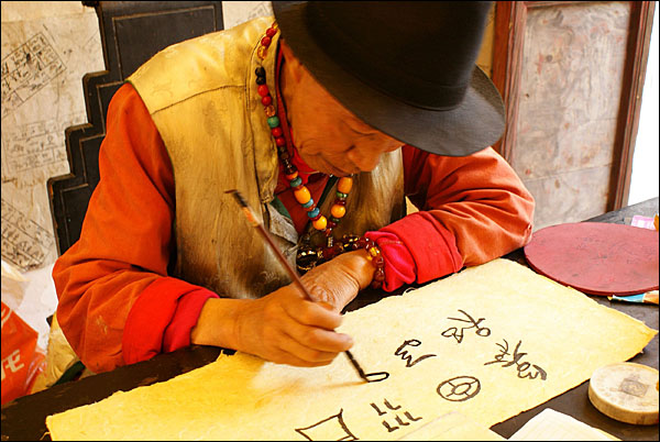 관광객이 산 전통종이에 동파문자를 써주는 동파. 동파교의 사제였던 동파는 오늘날 종이공방에 고용되어 동파문자를 써주며 살아가고 있다.