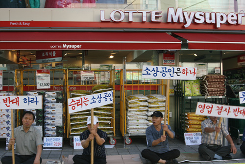 지자체의 일시정지권고에는 강제성이 없다. 권고를 위반하고 영업중인 롯데마이수퍼 묵동점 앞에 인근 상인들이 집회를 열고 있다. 