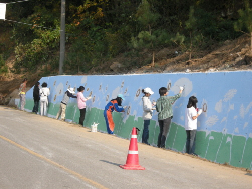 북면 양곡리 진입로 옹벽에 벽화를 그리고 있는 모습.