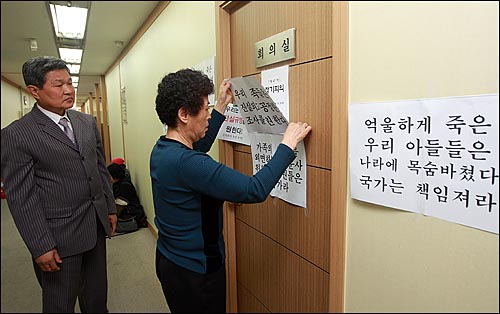 지난 2009년 10월 21일 오전 서울 중구 군의문사진상규명위원회 회의실 앞에서 군의문사 유가족들이 진실규명을 위한 공정한 조사를 촉구하는 내용의 종이를 붙이고 있다.