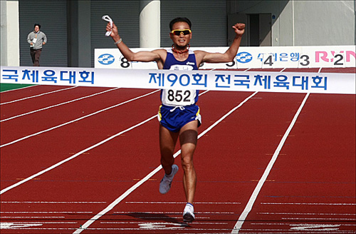  이봉주 선수가 '제90회 전국체육대회' 마라톤 경기에서 1위로 결승선을 통과하고 있다. 이봉주 선수는 이번 대회를 끝으로 은퇴했다.