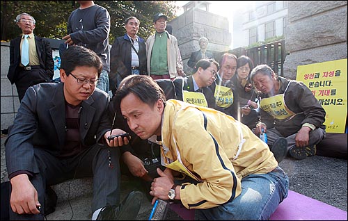 '언론관련법' 국회 표결의 정당성을 가리는 권한쟁의심판 청구 사건에 대한 헌법재판소의 선고가 있는 29일 오후 서울 종로구 재동 헌법재판소 앞에서 시민들이 휴대폰 DMB를 통해 헌법재판소의 결정을 경청하고 있다.
