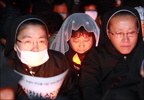  성직자들과 시민들이 2일 밤 서울광장에서 열린 '죽은 자들과 죽어가는 뭇 생명들을 위한 위령미사'에서 경찰에 둘러싸인 채 용산참사 희생자들의 넋을 기리며 시국미사를 드리고 있다.