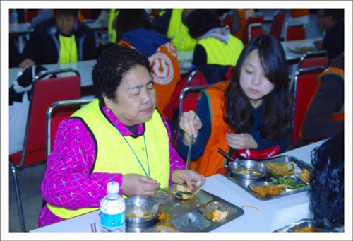  시각장애인에게 음식을 날라와 정성스럽게 떠 먹여주는 자원봉사자. 