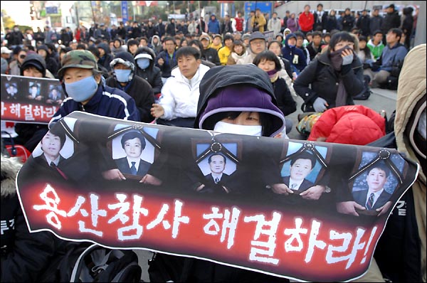 용산참사가 일어난지 300일을 하루앞둔  14일 오후 서울역 광장에서 개최된 '용산참사 300일 범국민 추모대회'에서 한 참가자가 용산참사 해결하라는 현수막을 펼쳐보이고 있다.