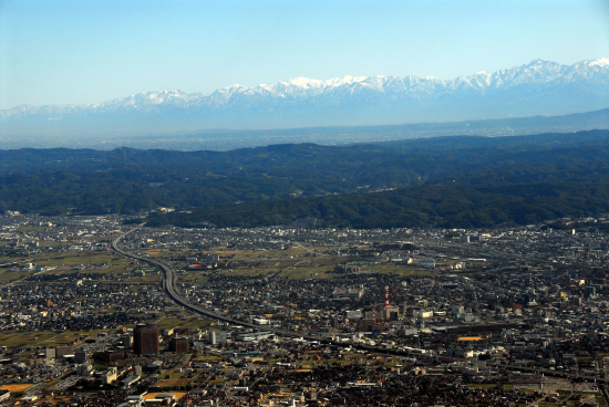 눈 덮인 북알프스 연봉連峰을 배경으로한 이시카와현의 현청소재지인 가나자와시 

