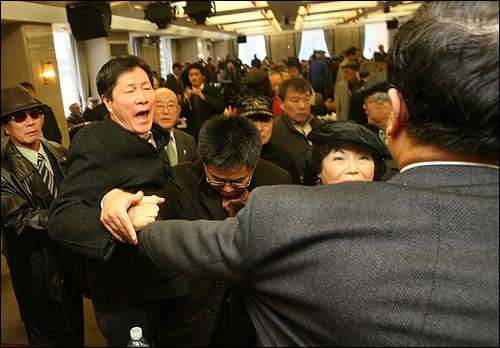 한 참가자가 기자회견 연단에 있던 추최측 인사의 팔을 잡아 당기며 항의하고 있다.