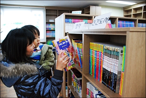 사천시 용현면 동강아뜨리에 아파트에 있는 한 작은도서관에서 엄마와 아이가 책을 고르는 모습. 최근 작은도서관에도 운영비를 지원할 수 있도록 조례를 만들자는 의견이 흘러나오고 있다.