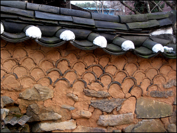 돌을 다듬지 않고 밑부분에 놓았고, 위에는 수키와를 엎어 문양을 만들었다. 독특한 담장 문양이 이 집의 특징이기도 하다.