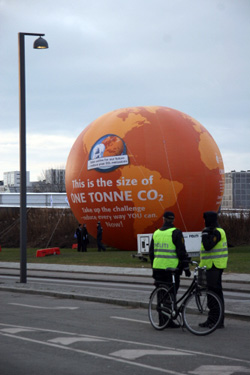 제15차 유엔기후변화협약 당사국회의(COP15)가 열리는 코펜하겐 벨라센터에서 자전거를 탄 경찰이 CO2 감축을 호소하는 풍선 앞에 서 있다.