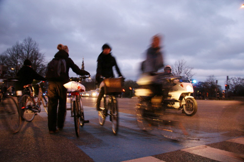 제15차 유엔기후변화협약 당사국회의(COP15)가 열리는 코펜하겐 시내에서 시위대의 행진 때문에 경찰이 교통을 통제하는 가운데 시민들이 자전거를 타고 가고 있다.