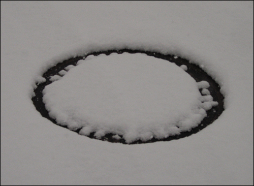 눈 내리는 날. 동그라미를 그린 맨홀 뚜껑이 이색적입니다.