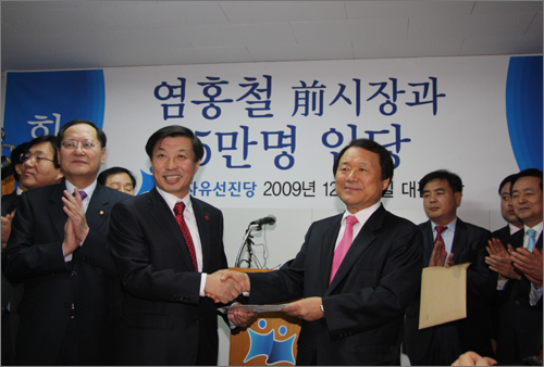 염홍철 전 대전시장(오른쪽)이 23일 자유선진당 이재선 대전시당 위원장에게 입당원서를 내고 있다.