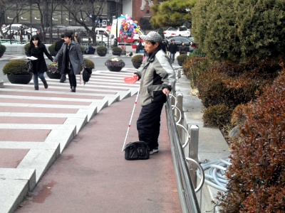 한 시각장애인이 명동성당 입구에서 구걸하고 있다.