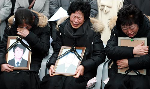 30일 기자회견이 진행되는 동안 사망한 남편의 영정사진을 껴안고 있는 용산참사 유가족들이 오열하고 있다.