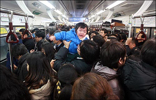 41년 만에 기록적인 폭설이 내린 지난 1월 4일 저녁 서울 1호선 지하철에서 한 시민이 퇴근하는 시민들로 가득찬 열차안에서 극심한 혼잡을 피해 힘들어하는 아이를 들어올리며 달래고 있다.  