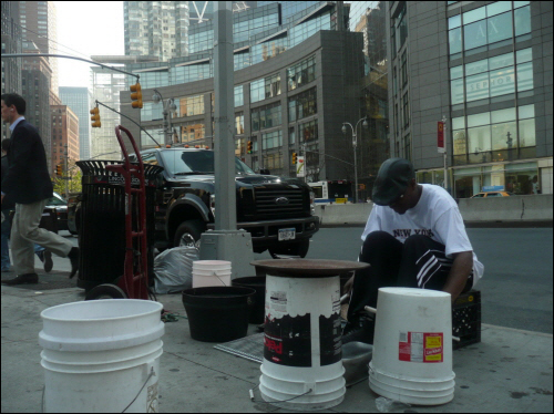 세계경제중심이었던 뉴욕도 경기침체로 큰 어려움을 겪고 있다. 뉴욕의 한 흑인이 거리에서 주운 재활용품을 활용해 연주를 하고 있다. 