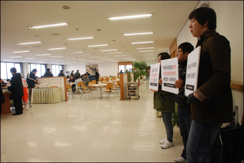 지난 4일, 학생들이 교직원 식당에서 한 시간 가량 학내복지사업 일방적 외부업체 매각을 반대하는 손팻말을 들었다.