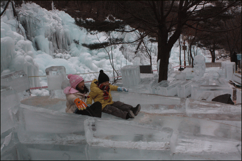 얼음조각으로 만든 미니 썰매장에서 어린 아이들이 신나게 얼음썰매를 타고 있는 광경.