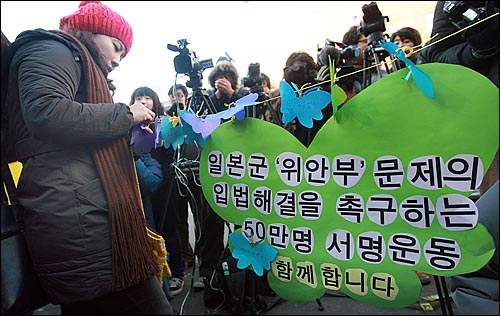 13일 정오 서울 종로구 주한일본대사관 앞에서 열린 900회 수요집회에서 여성단체 참가자들이 일본군 위안부 강제동원 문제해결을 촉구하는 글을 나비 모양의 종이에 적어 끈에 매달고 있다.