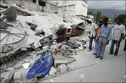  규모 7.0의 강진이 휩쓸고 간 아이티 수도 포르토프랭스 주민들이 13일 지진으로 무너진 건물더미와 그 위에 널브러져 있는 시신들을 쳐다보고 있다.