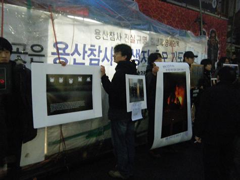 청년들이 남일당 앞에서 용산 참사의 부당함을 깜작 사진전으로 알리고 있다.