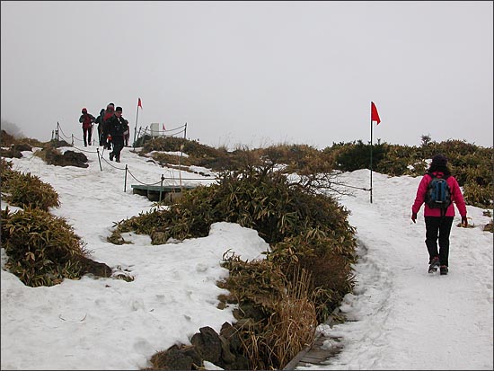 등산로에 눈이 덮여 길을 분간하기 어렵다. 빨간 깃발을 따라가야 한다.