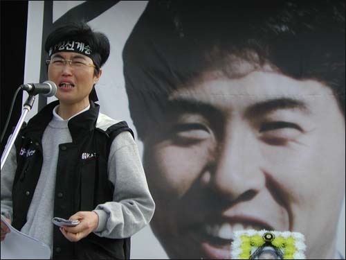 2003년 10월22일 김진숙이 한진중공업 김주익 지회장의 대형 영정 앞에서 추도사를 낭독하고 있다.