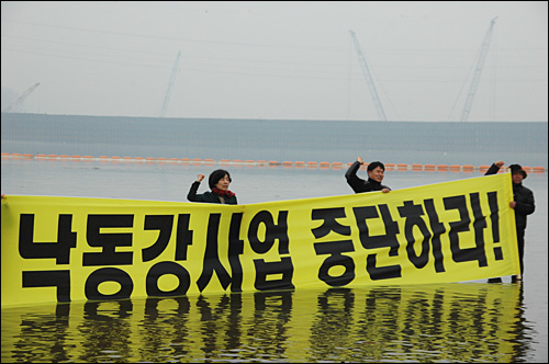 낙동강국민연대는 9일 오후 함안보 아래 낙동강에 들어가 대형 펼침막을 들고 시위를 벌였다.