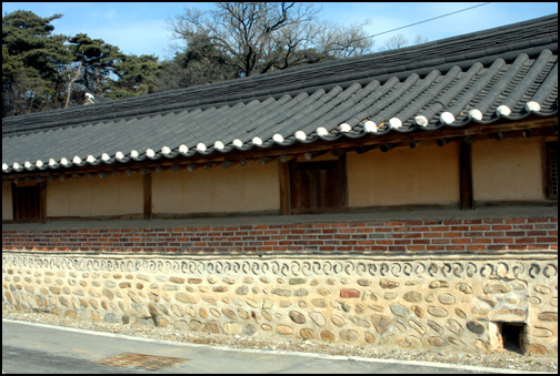 대문 좌우에 마련한 행랑채의 담벼락이 외벽이다. 벽돌과 기와, 돌을 이용해 쌓은 문양이 특이하다.