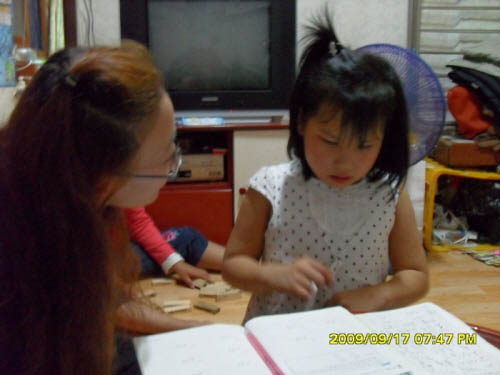 아이가 학생의 도움을 받아 학습하는 모습.