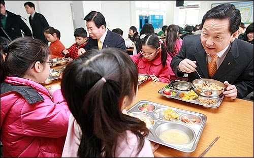 김상곤 경기도교육감과 김진표 민주당 의원(오른쪽부터)이 2010년 3월 10일 평택 갈곶초등학교에서 3학년 학생들과 함께 무상급식을 먹으며 이야기를 나누고 있다.