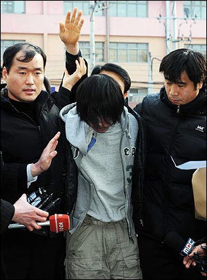 부산 여중생 L양(13)을 납치 살해한 피의자 김아무개(33)씨가 지난 10일 오후 부산 사상구 덕포시장에서 검거돼 사상경찰서로 압송된 가운데 한 시민이 손을 들어 피의자를 때리려 하고 있다.