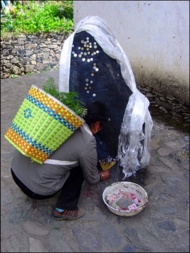 동전을 붙이고, 향을 사르며 기도를 하는 티베트인