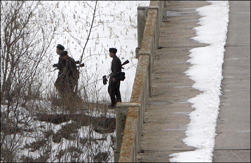 총을 든 북한군이 두만강변을 순찰하고 있다.
