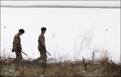 중국군이 곤봉을 들고 두만강변을 순찰하고 있다.