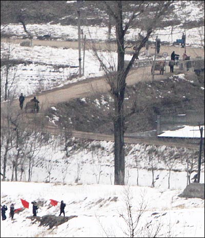 3월 19일 낮 중국 연변자치주 투먼시에서 바라본 북한 함경북도 남양시. 붉은 깃발을 들거나 달구지와 자전거를 끌고 가는 주민들의 모습이 보인다.