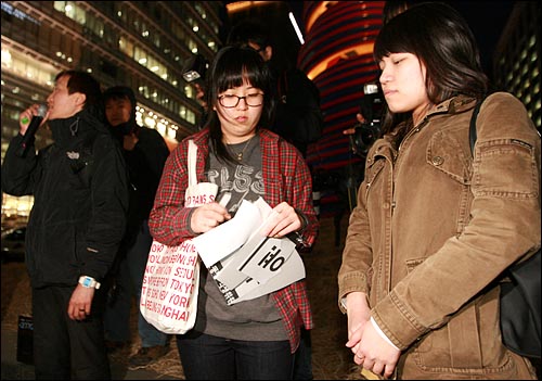 한 여학생이 부서진 피켓 조각을 들고 서 있다.