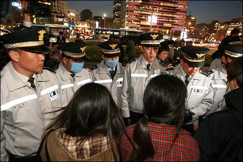 촛불을 뺏어간 뒤에도 경찰들이 참가자들을 에워싸고 있다.