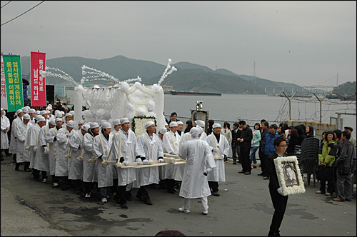김주열 열사 범국민장이 11일 마산 중앙부두에서 열렸다. 사진은 시신 인양지인 마산 앞바다를 뒤로 하고 상여를 메고 운구하고 있는 모습.