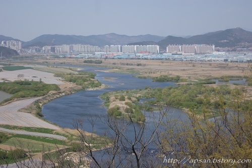 이곳은 낙동강과 금호강이 만나는 바로 그 합수 지점으로, 푸른 물이 흐르는 오른쪽 금호강의 제방 너머로 성서산업단지가 보인다.
